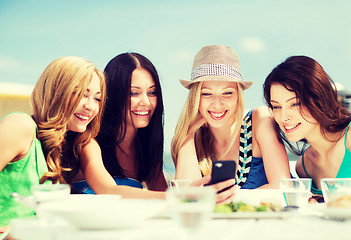 Image showing girls looking at smartphone in cafe on the beach