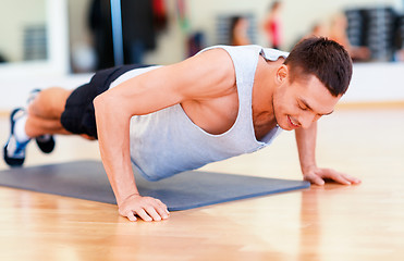 Image showing smiling man doing push-ups in the gym