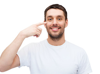 Image showing smiling young handsome man pointing to eyes