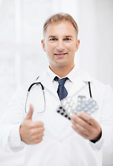 Image showing young male doctor with packs of pills