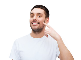 Image showing smiling young handsome man pointing to cheek