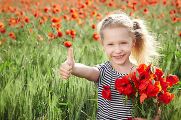Image showing Happy little girl on poppy meadow giving thumb up