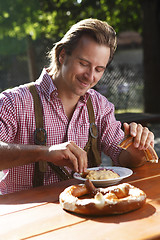 Image showing Attractive man eats traditional cheese in a Bavarian beer garden