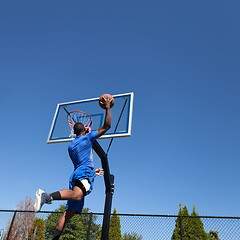 Image showing Basketball Player Slam Dunking