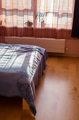 Image showing sun shade reflected through curtains on bedspreads 