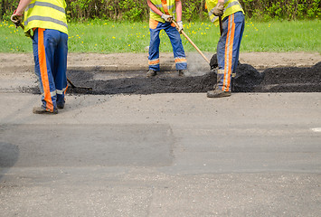 Image showing teamworker smoothing asphalt pavement new road  