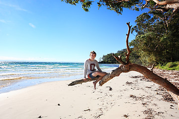 Image showing Cheerful teen boy sitting on tree  holiday at the beach Australi