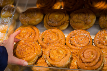 Image showing hand hold yeast bun with cinnamon in store 