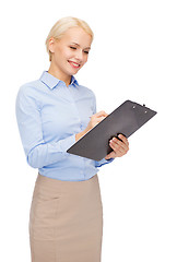 Image showing smiling businesswoman with clipboard and pen