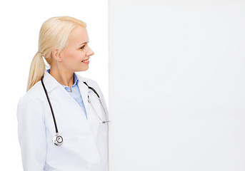 Image showing smiling female doctor with white blank board