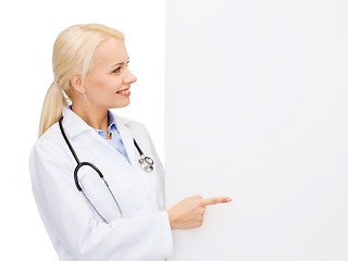 Image showing smiling female doctor with white blank board