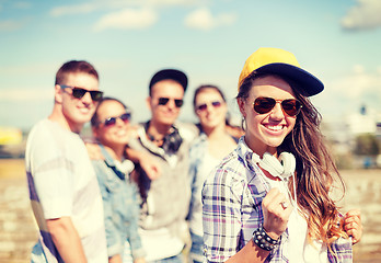 Image showing teenage girl with headphones and friends outside