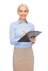 Image showing smiling businesswoman with clipboard and pen