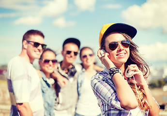 Image showing teenage girl with headphones and friends outside