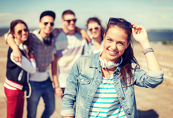 Image showing teenage girl with headphones and friends outside