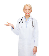 Image showing smiling female doctor holding something on hand