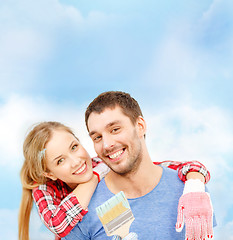 Image showing smiling couple covered with paint with paint brush