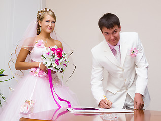 Image showing wedding. The groom signs the registration documents