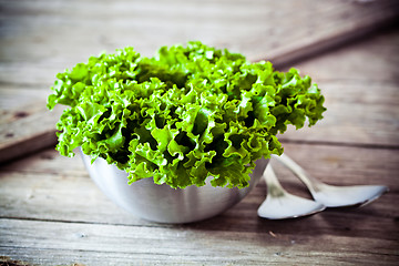 Image showing lettuce salad in metal bowl and spoons 