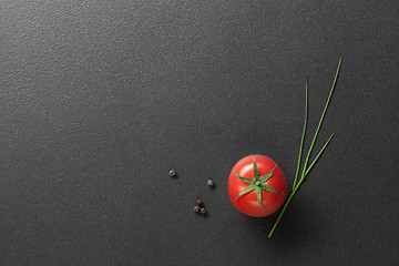 Image showing red tomato with green onion on black