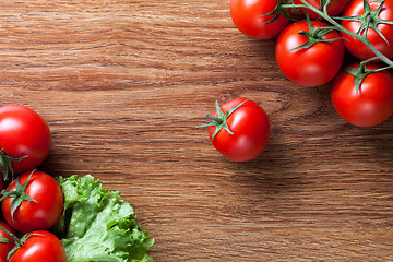 Image showing red tomatoes with green salad on wood