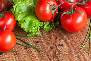 Image showing red tomatoes with green salad on wood