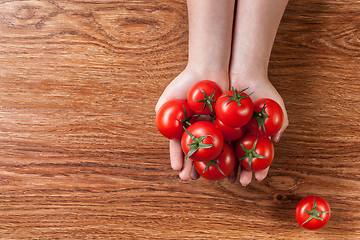 Image showing red tomatoes in hands on wooden background