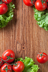 Image showing red tomatoes with green salad on wood