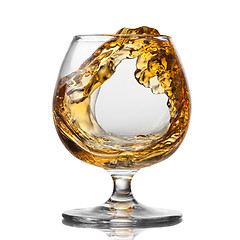 Image showing Splash of cognac in glass isolated