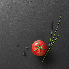 Image showing red tomato with green onion on black