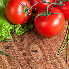 Image showing red tomatoes with green salad on wood