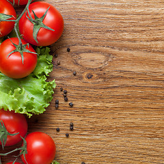 Image showing red tomatoes with green salad on wood