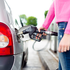 Image showing Lady pumping gasoline fuel in car at gas station.