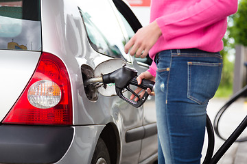 Image showing Lady pumping gasoline fuel in car at gas station.