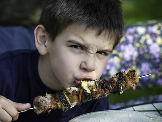 Image showing Child eating meat on a skewer