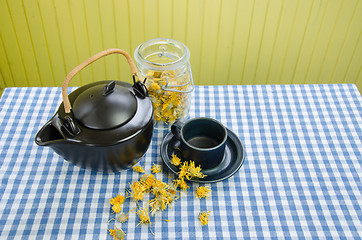 Image showing dried coltsfoot herbal on table and clay tea set 