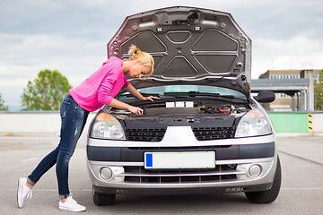 Image showing Woman inspecting broken car engine.