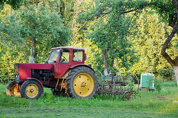 Image showing farm tractor with yellow wheels harow in garden  