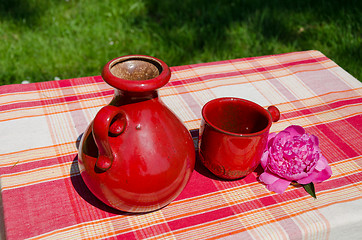 Image showing retro old teapot and red cup in nature background 