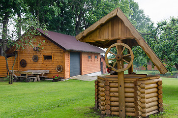 Image showing Rural well manhole decor and house made of logs