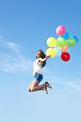 Image showing Happy young woman jumping with colorful balloons