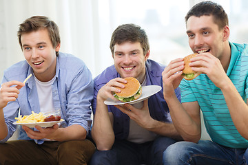 Image showing smiling friends with soda and hamburgers at home