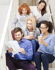 Image showing team with papers and take away coffee on staircase