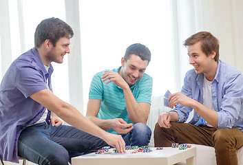 Image showing happy three male friends playing poker at home