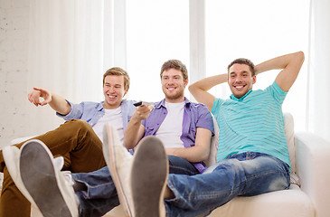 Image showing smiling friends with remote control at home