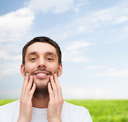 Image showing beautiful smiling man touching his face