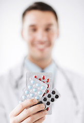 Image showing male doctor with packs of pills