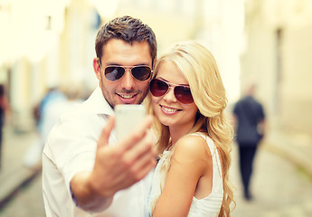 Image showing smiling couple with smartphone in the city