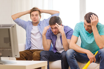 Image showing sad male friends with vuvuzela watching sports