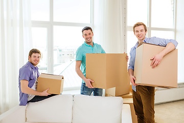 Image showing smiling male friends carrying boxes at new place